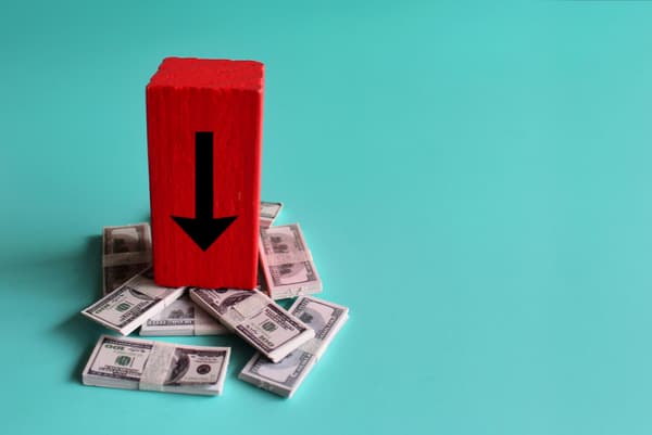 A red block with a black arrow atop a bundle of $100 bills A red block with a black arrow atop a bundle of $100 bills