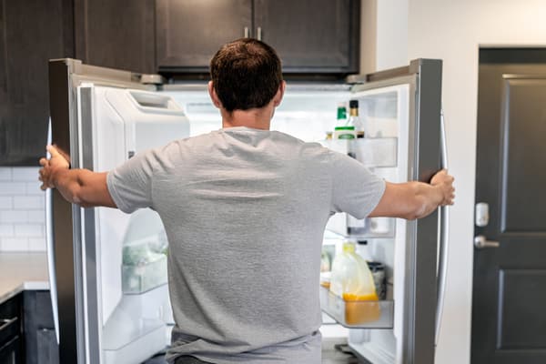 A man holding a GE French door refrigerator open