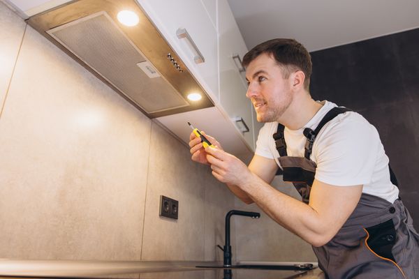 A technician installing a range hood 