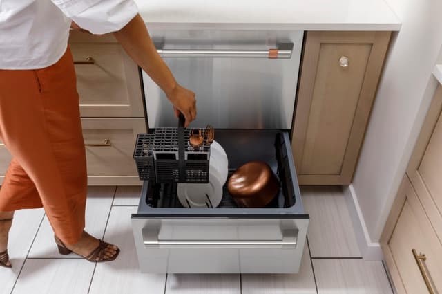 Front view of a woman unloading her drawer dishwasher from Cafe