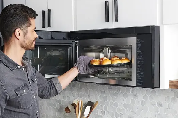 A man pulling buns out of the LG MHEC1737F microwave