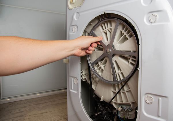 A person accessing a washer drum belt 