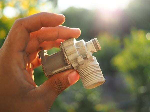 iStock Credit: Phu Min A person holding a washer inlet valve