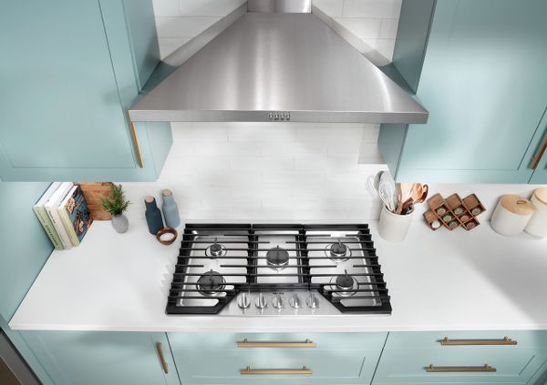 Overhead view of the Whirlpool WCGK5036PS 36” cooktop in a blue-themed kitchen 