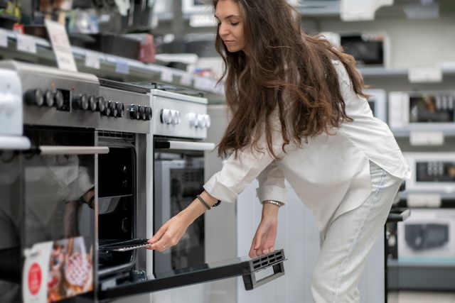 Front view of a woman shopping for a range in an appliance tore