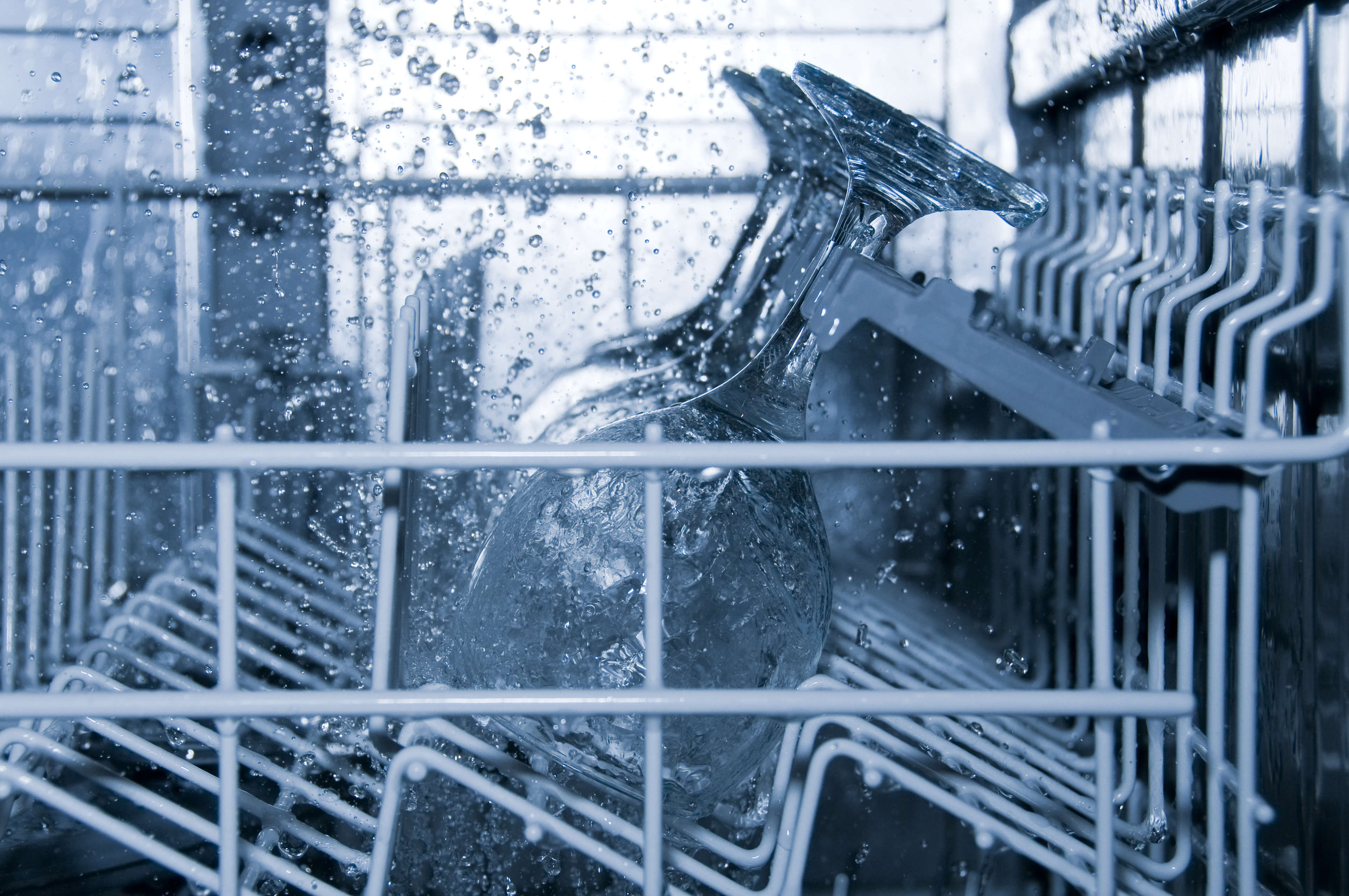  The inside of a dishwasher in operation cleaning wine glasses 
