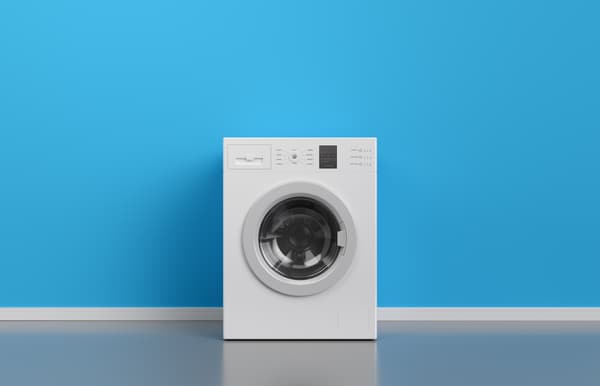 A front load washing machine against a blue wall