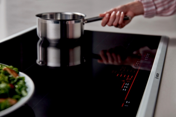 Benchmark A close up of a woman cooking on a Benchmark induction cooktop