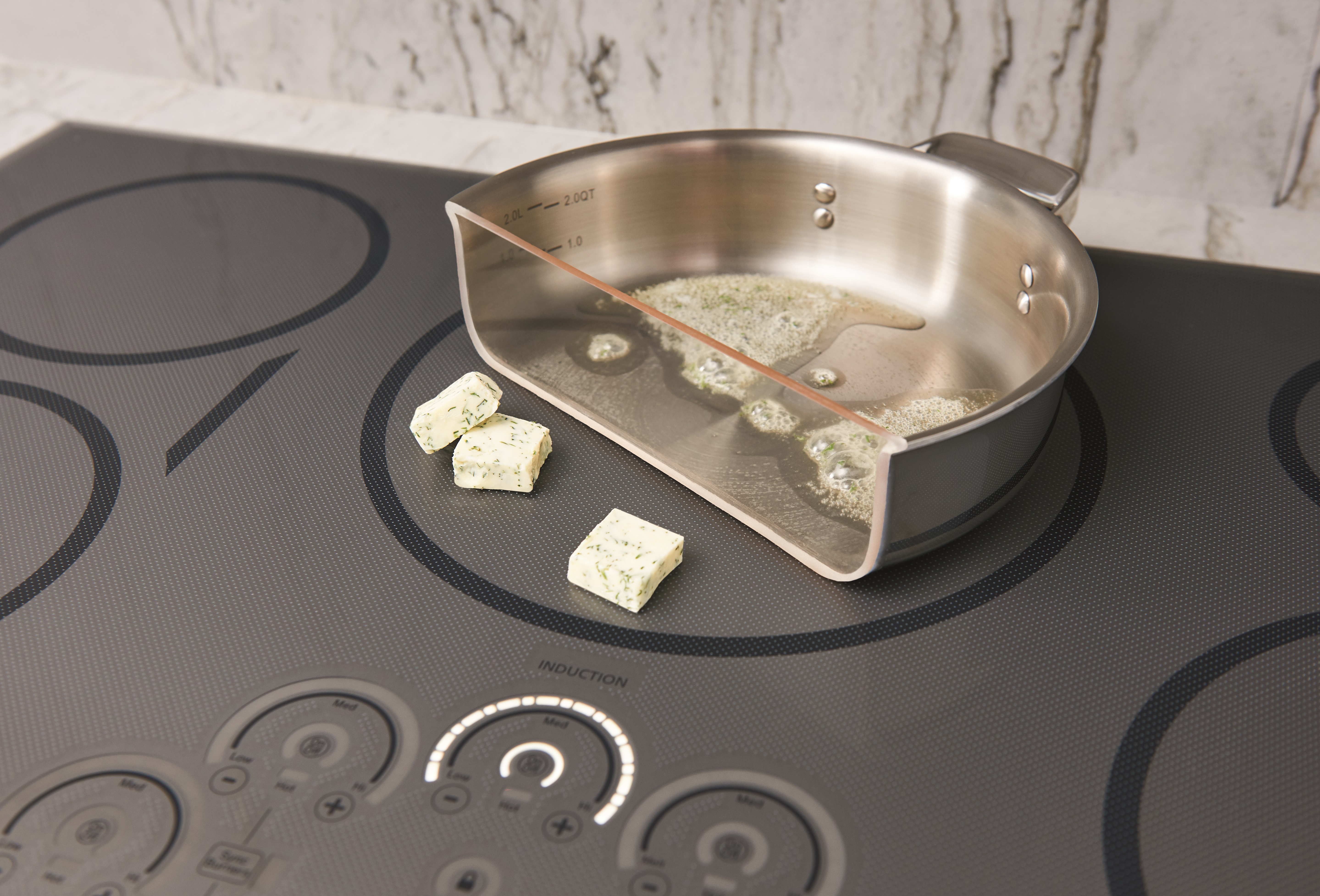 Café A Café induction cooktop shown with a pot cut in half demonstrating butter melting only on the cookware