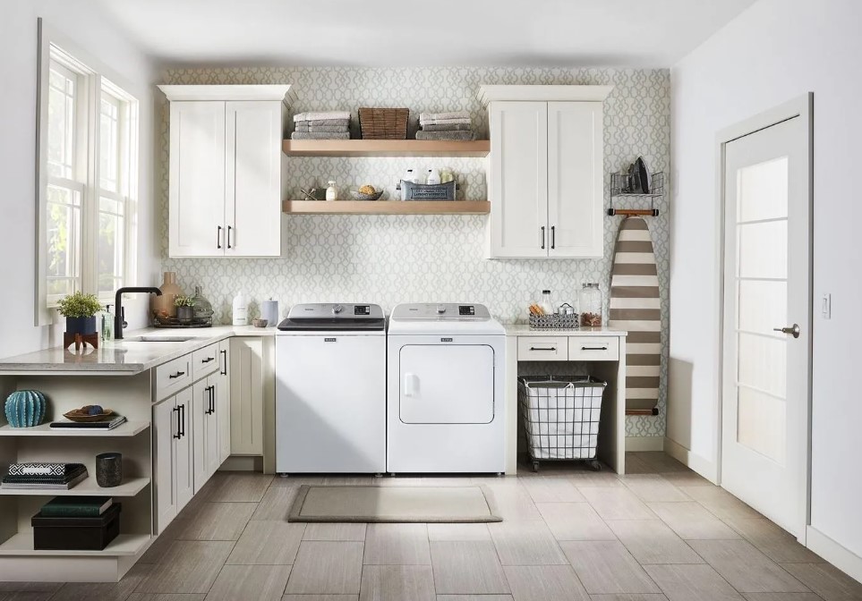 Maytag top load washer and dryer are situated in a white, well appointed laundry room
