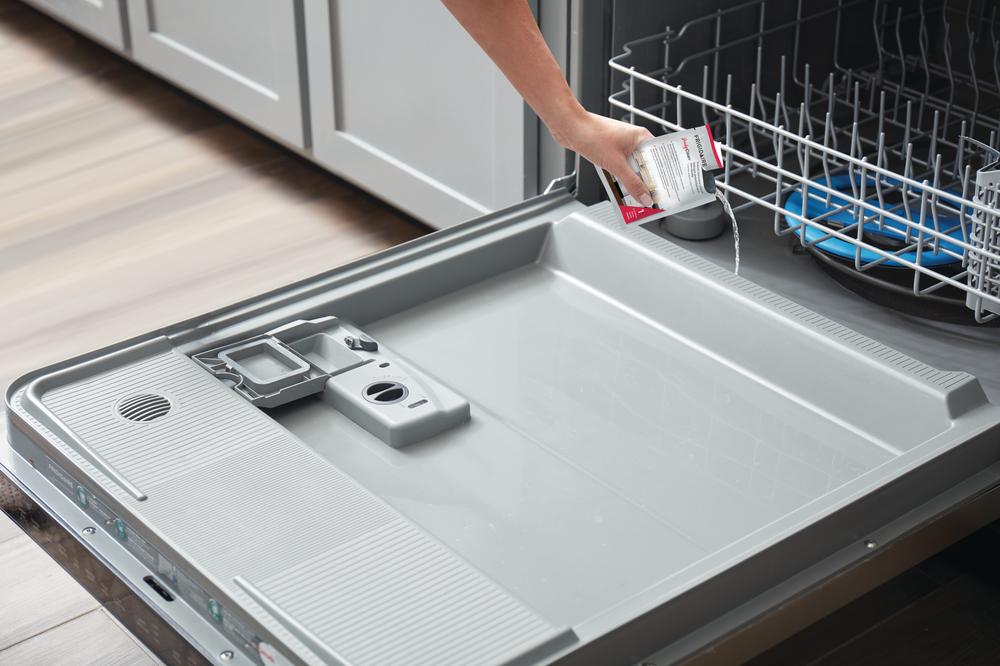 female hand pours probiotic cleaner to maintain her dishwasher