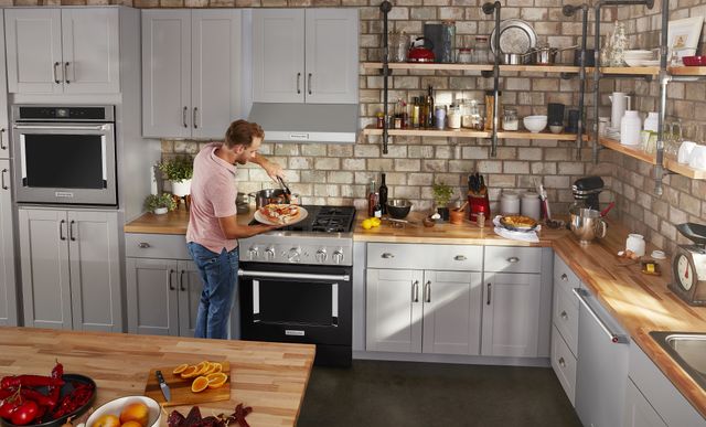 Front view of a man cooking in a home kitchen on a dual fuel range