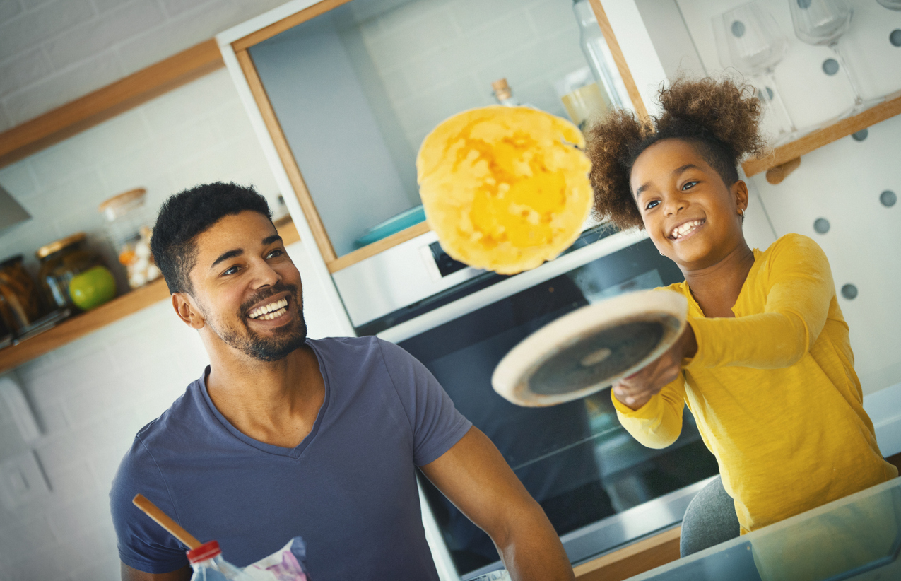 iStock Credit: gilaxia father and daughter have fun flipping pancakes over induction cooktop
