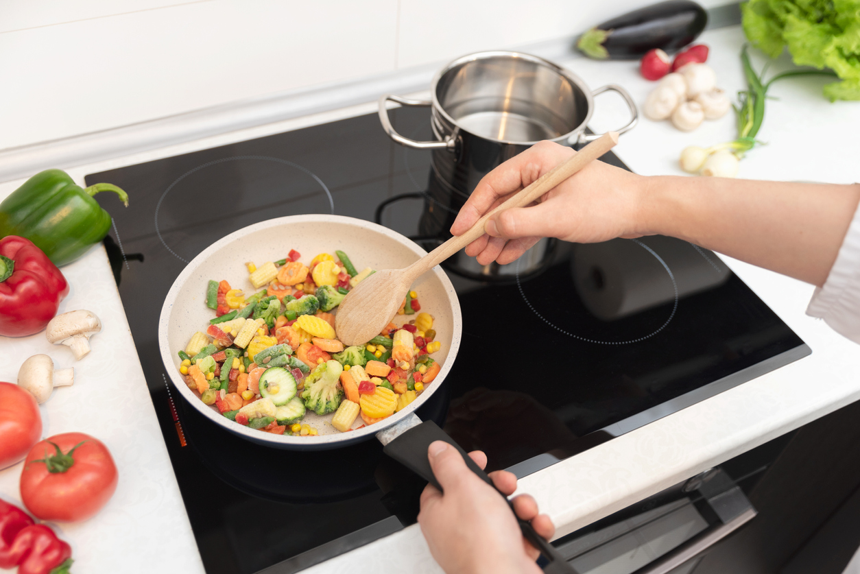 vegetables fried in a pan on a black induction cooktop