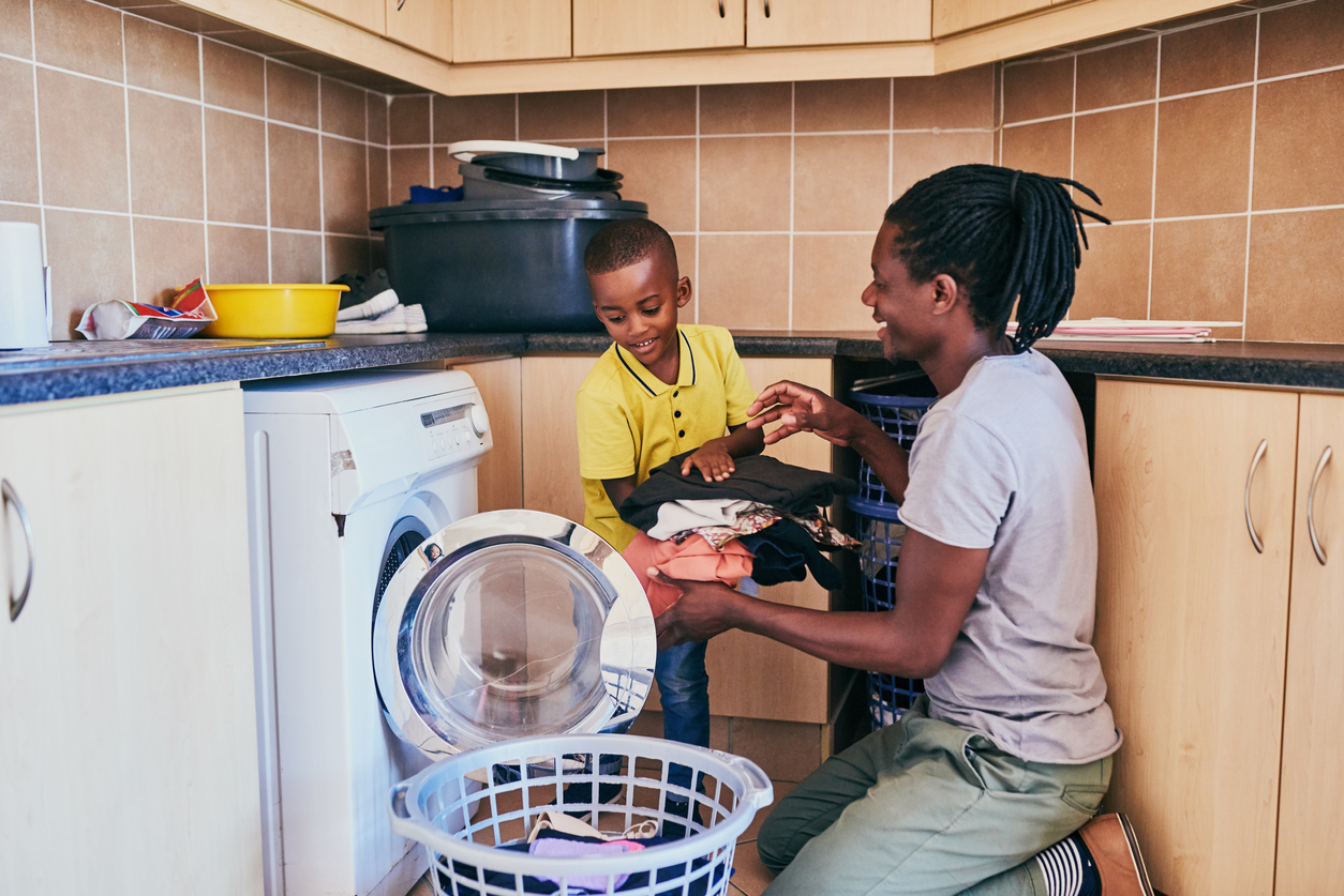 Credit:Moyo Studio Dad and his son taking laundry out of the dryer