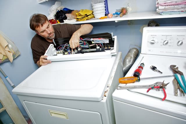 Close view of a man looking for the issue in the internal dryer components Close view of a man looking for the issue in the internal dryer components