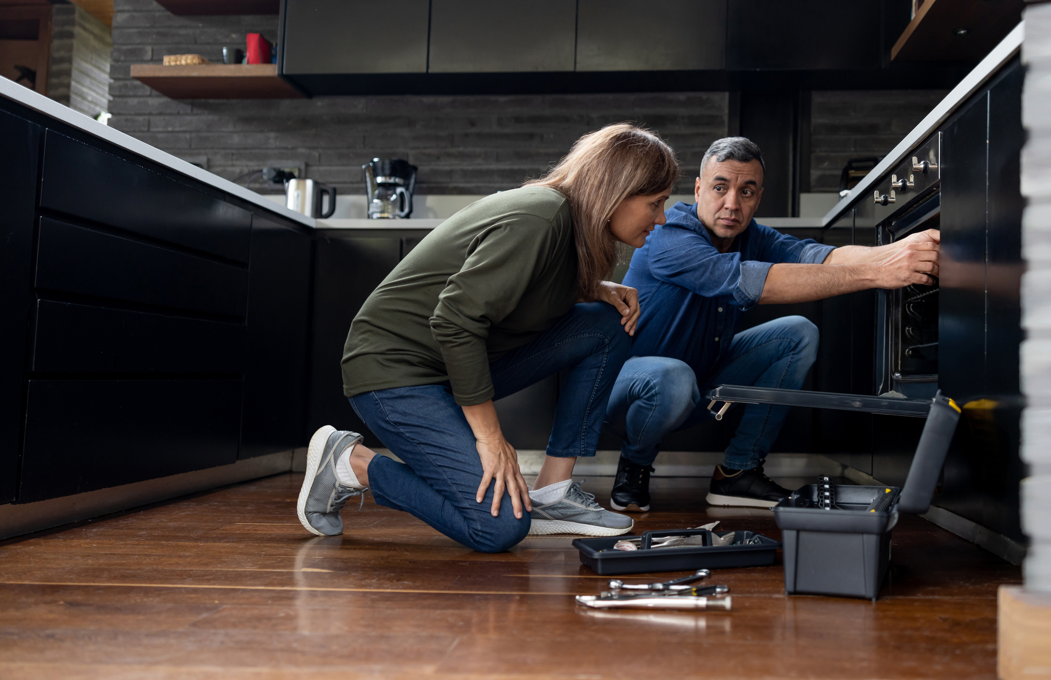 iStock Credit: andresr A repair man showing a woman an oven fix