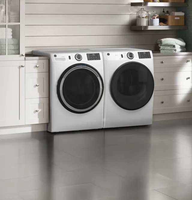 A GE GFW550SSNWW front load washer and matching dryer in a laundry room 
