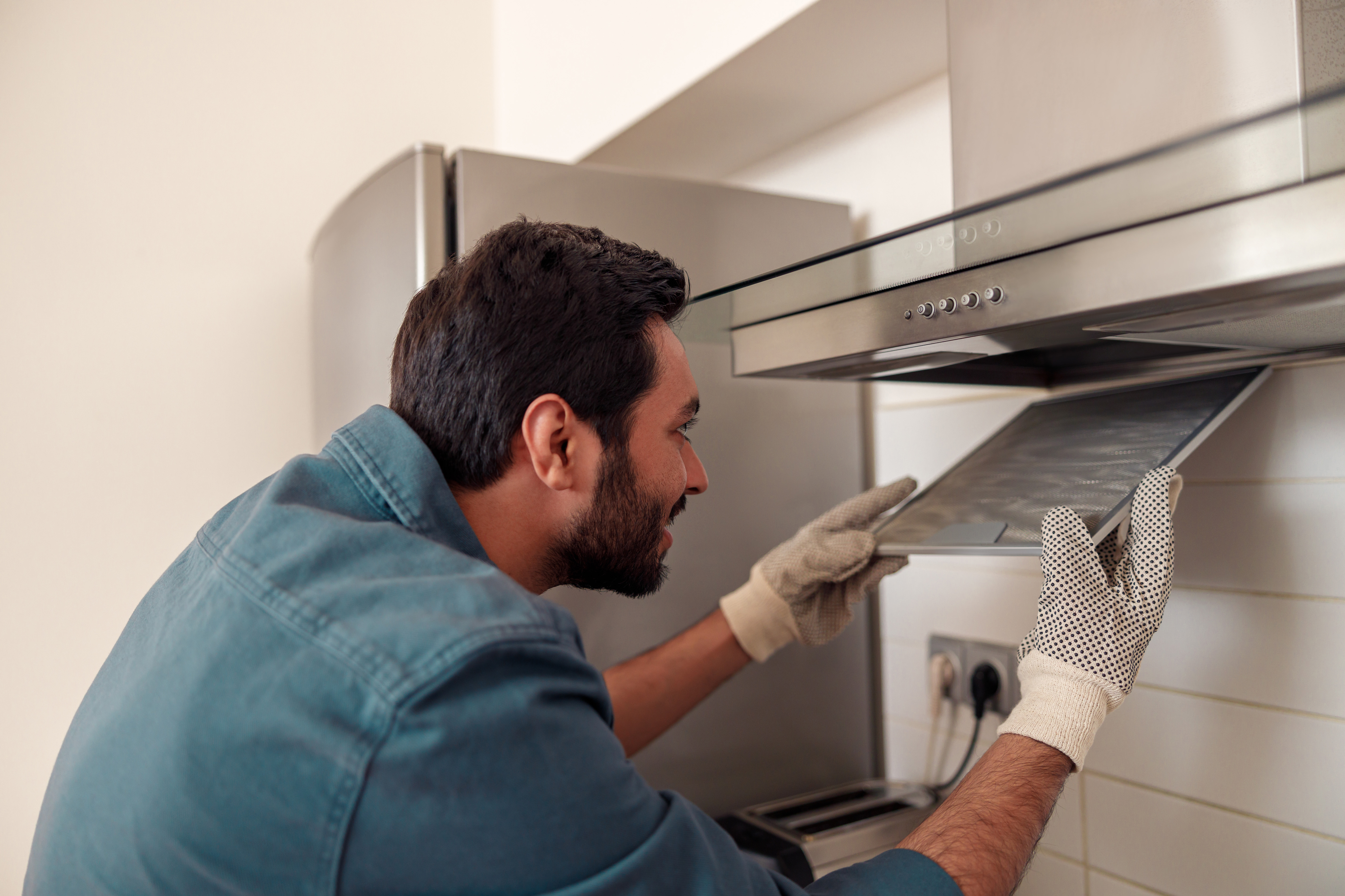 An appliance technician inserting a range hood filter 