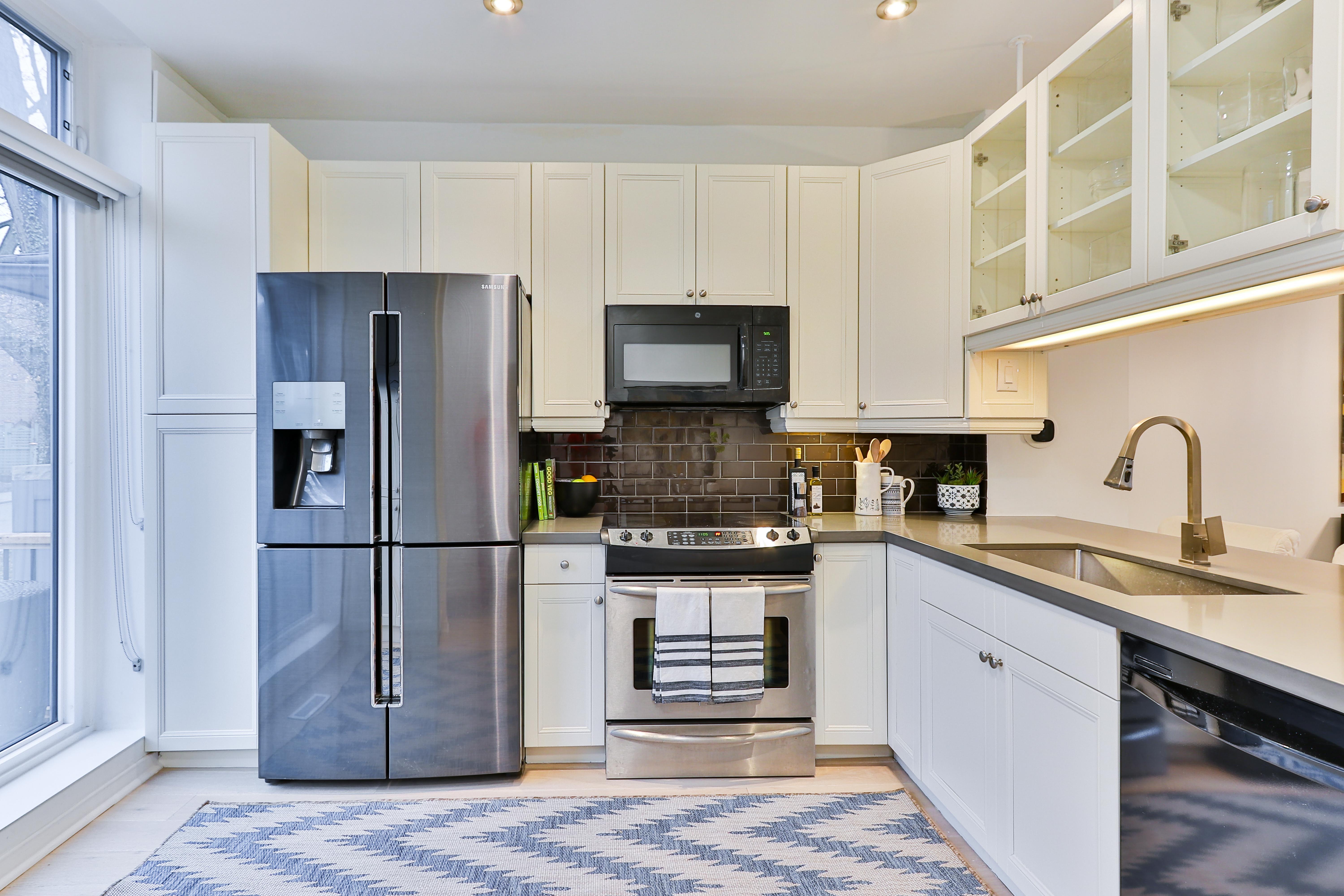 A wide shot of an L-shaped kitchen featuring a 4-door French door refrigerator