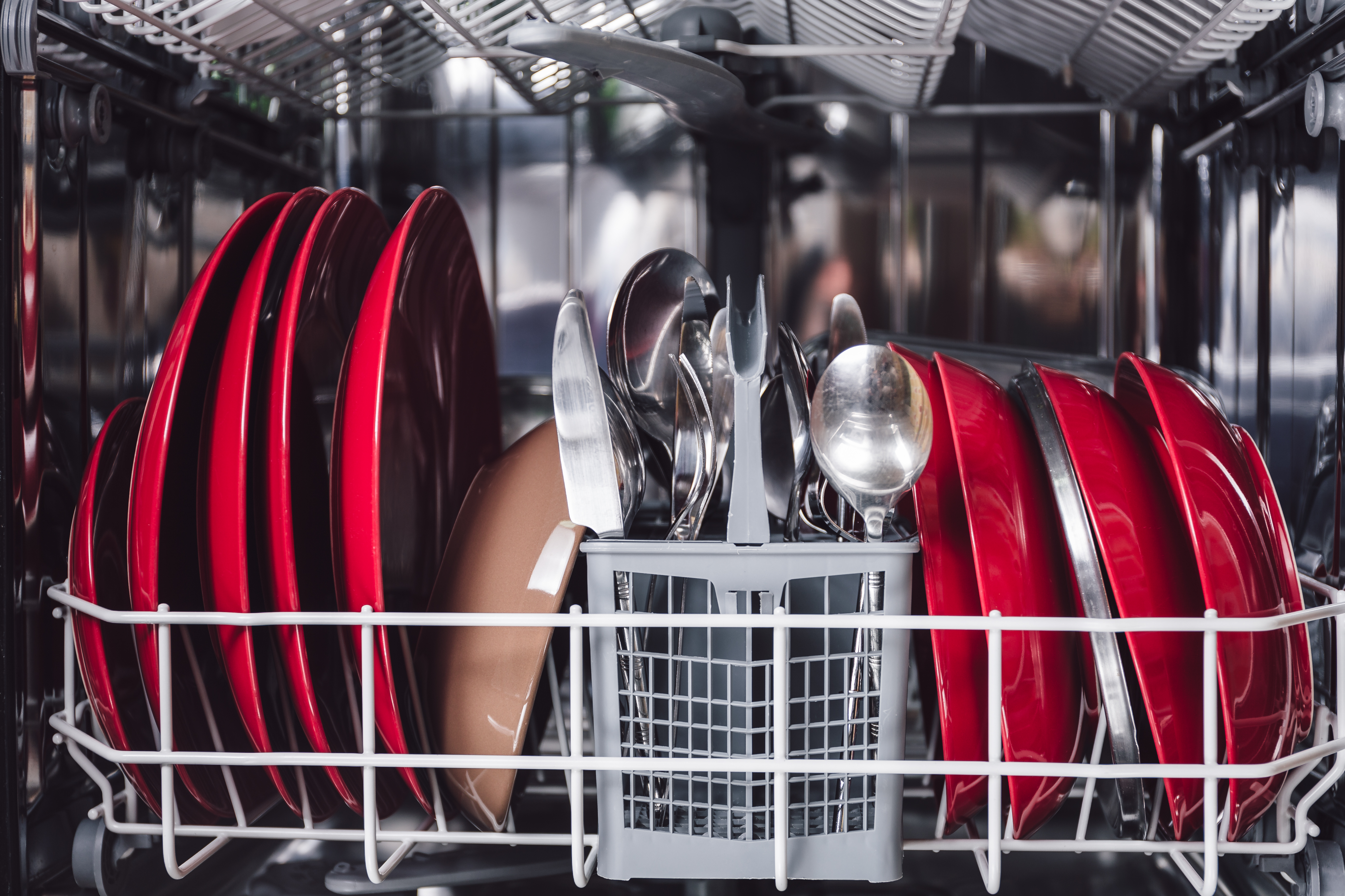 A dishwasher loaded with red dinnerware 