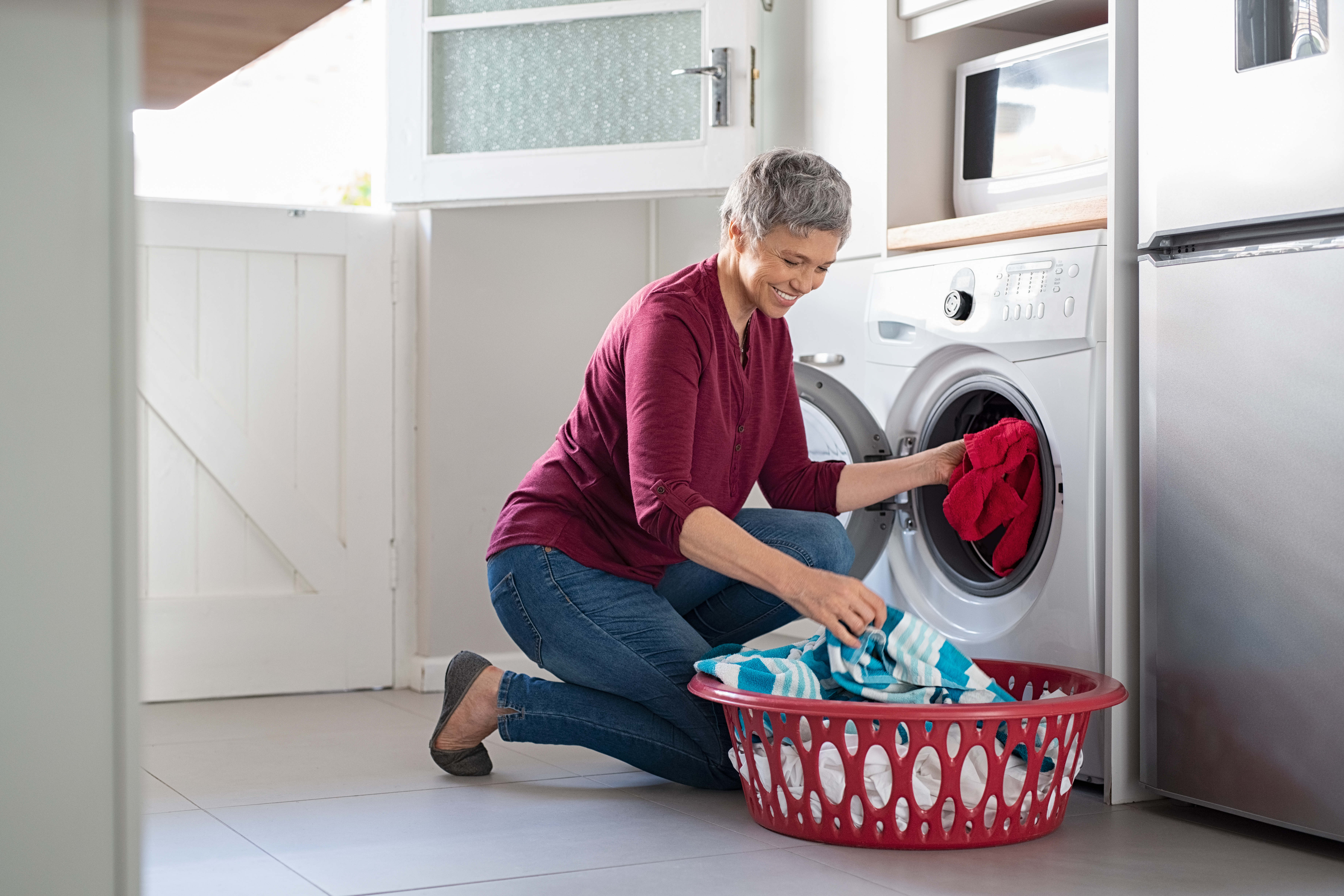 iStock Credit: Ridofranz woman in burgundy shirt and jeans taking clothes our of front load washer