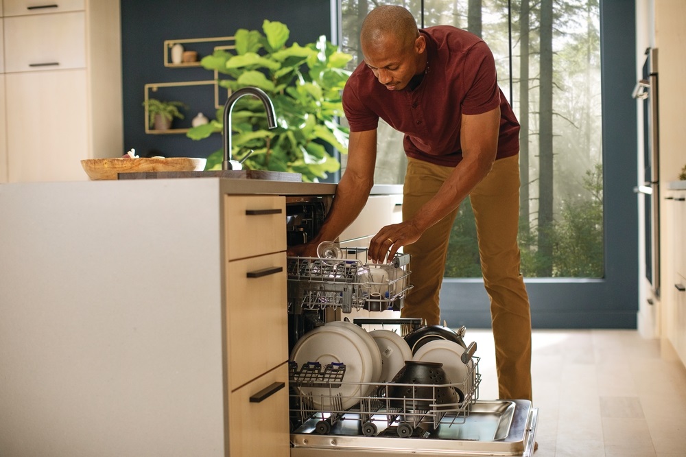 man pulls out racks of Electrolux dishwasher to unload clean dishes