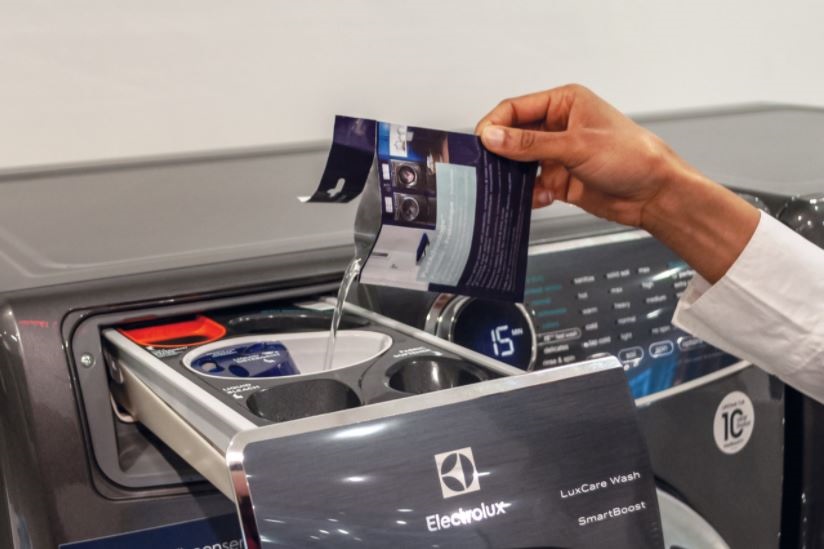 closeup of hand pouring powder detergent in an Electrolux washer’s Adaptive Dispenser