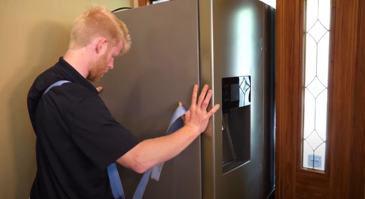 Grand Appliance installation pro sliding a fridge through a front door