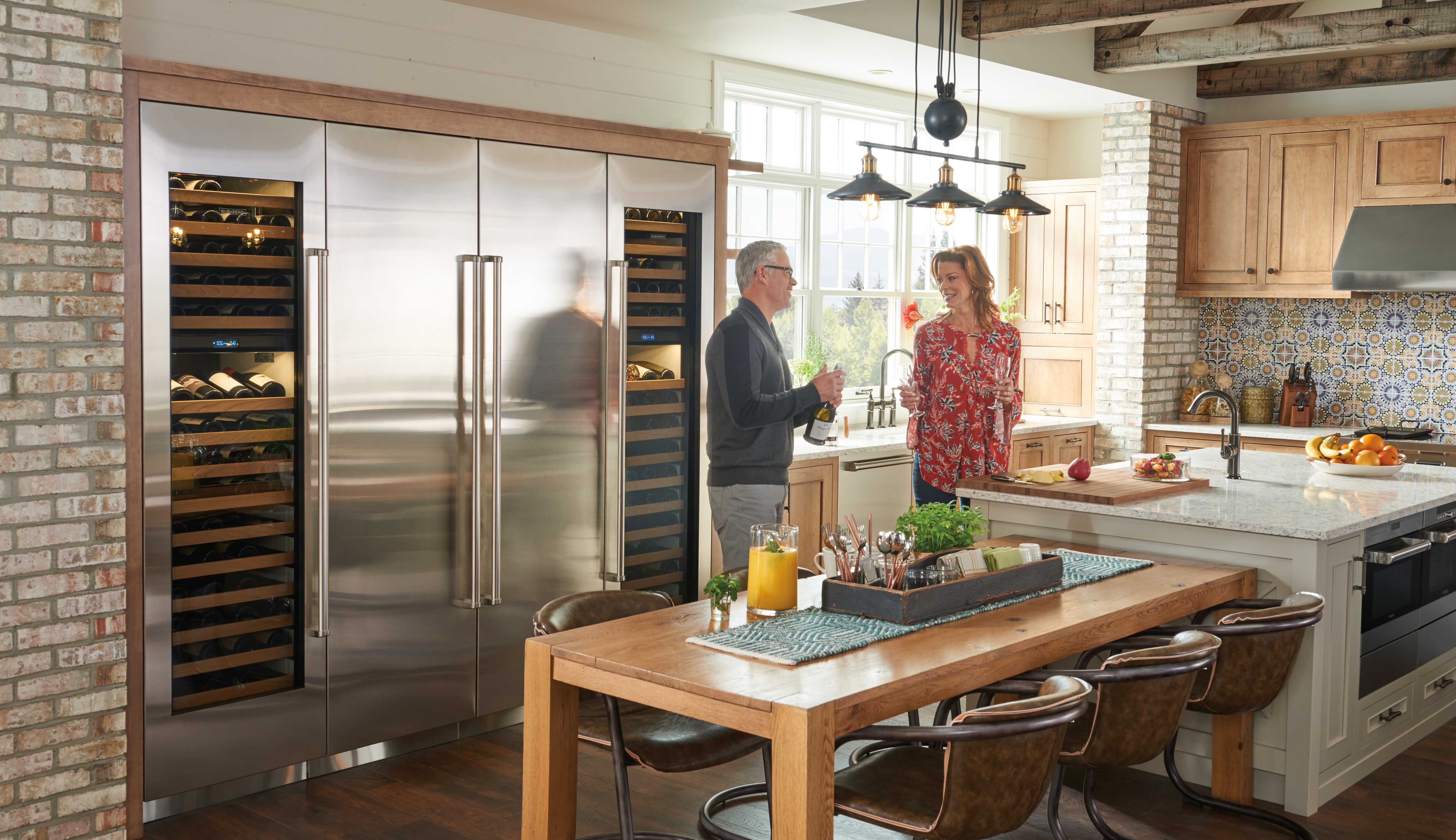 Husband and wife stand in pro-style kitchen next to a series of stainless-steel column refrigerators
