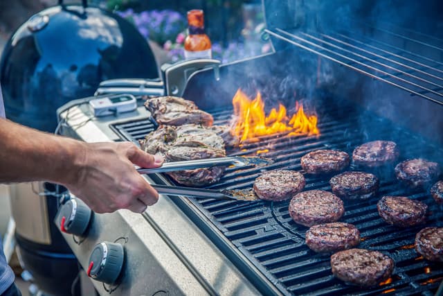 Credit: iStock Front view of someone cooking steaks on high heat on a flame grill