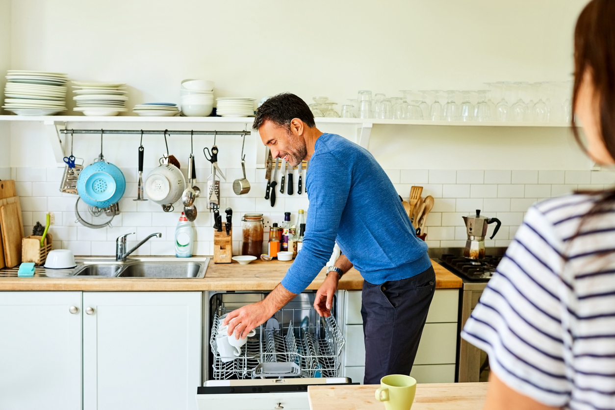 man putting coffee mugs in dishwasher