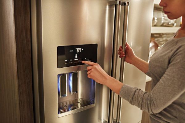 A person using the water dispenser on a KitchenAid refrigerator