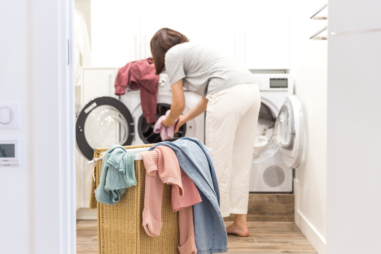 A woman does laundry using a front load washer and dryer
