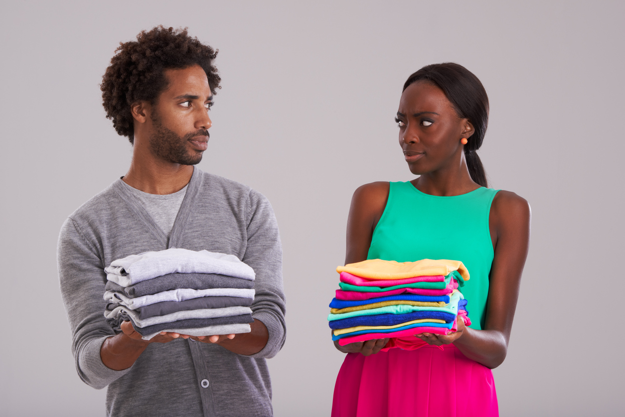 Credit:PeopleImages couple holding stacks of folded laundry separated by color
