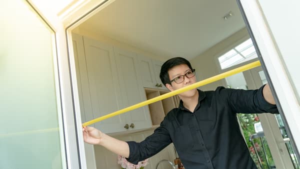 iStock Credit: Zephyr18 A man measuring a doorway
