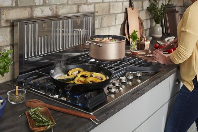 Front view of a woman cooking on a downdraft cooktop 