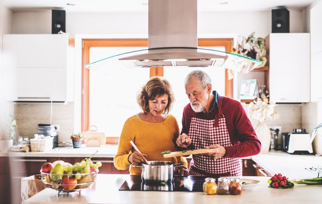 Front view of a couple cooking under an island range hood 