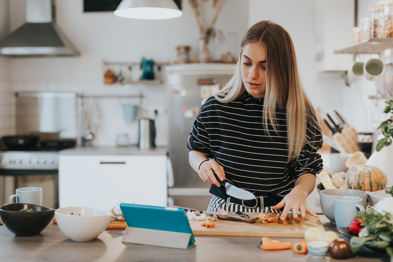 iStock Credit: visualspace Young woman cooks using a recipe management app