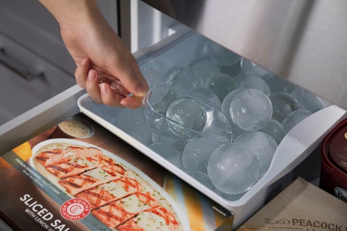 woman’s hand scoops LG slow-melting round ice into glass cup