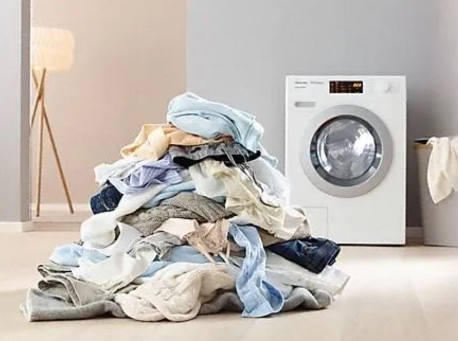 small washer and dryer pile of dirty clothes
