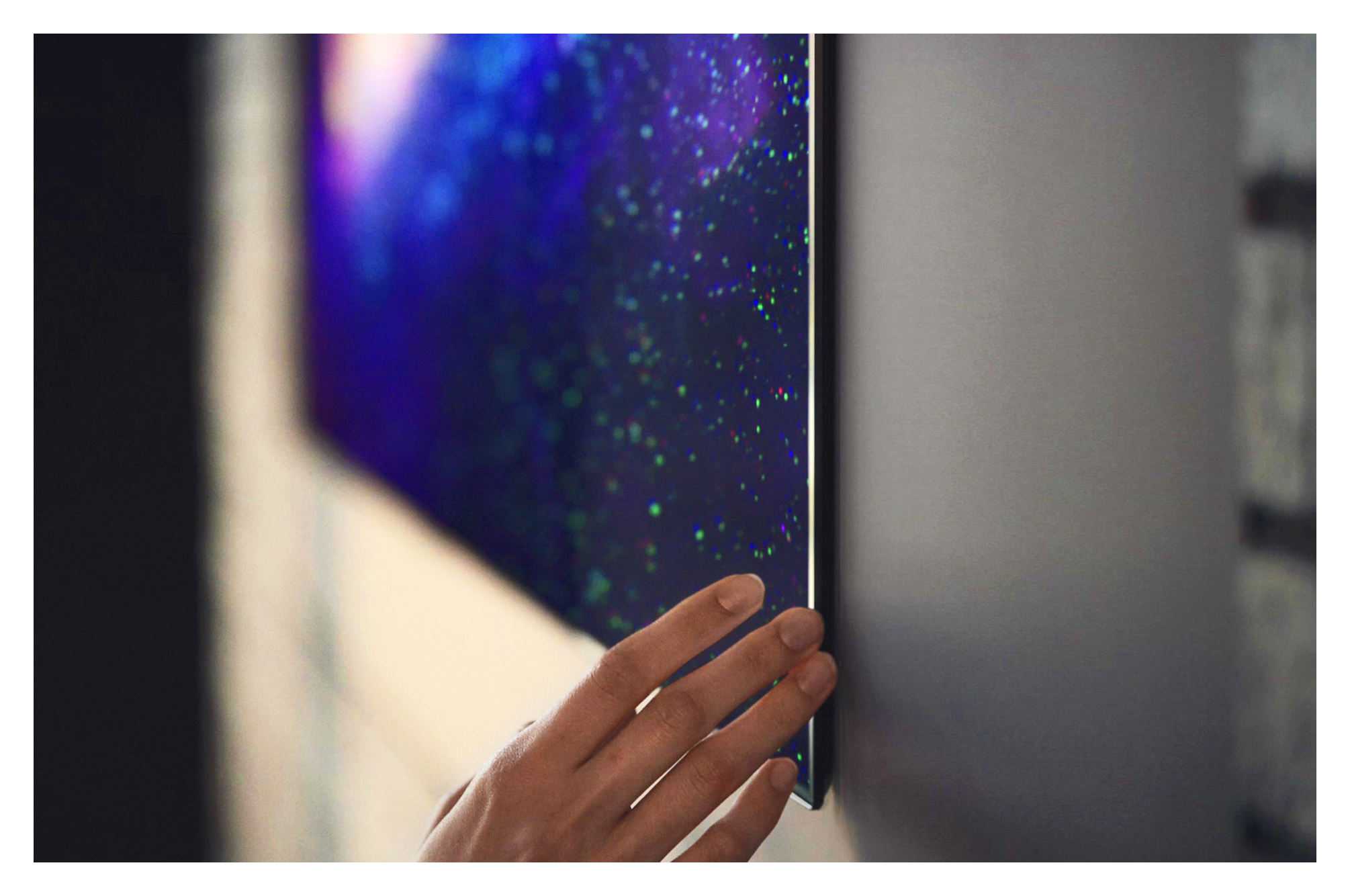 Side profile of thin LG OLED TV next to a hand 