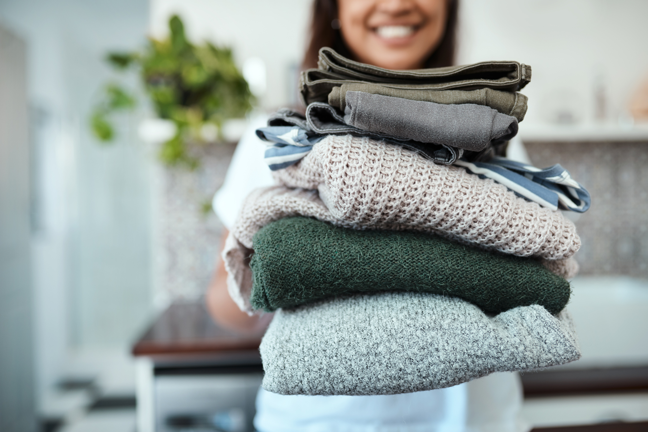 PeopleImages woman holding a stack of clean laundry
