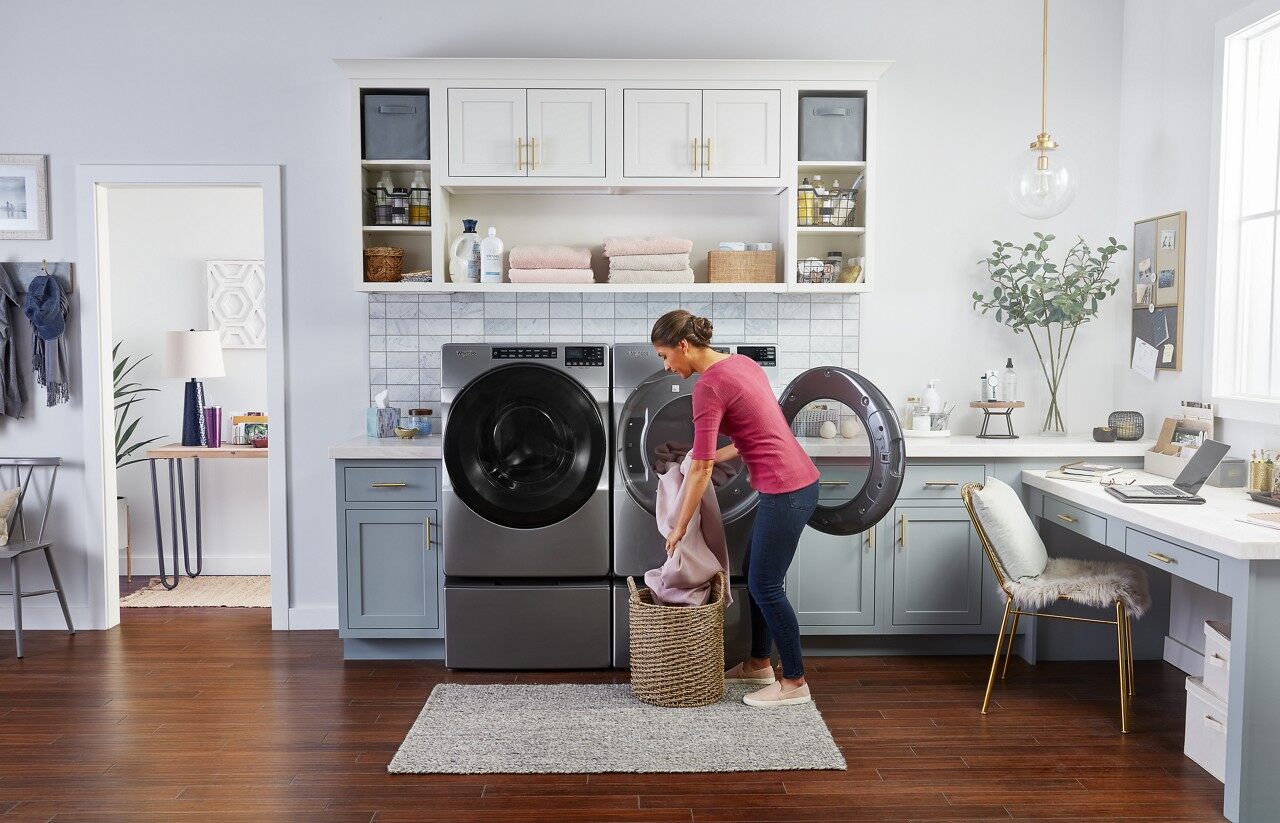 Credit: Whirlpool A woman loading clothes into a Whirlpool front load washer and dryer pair