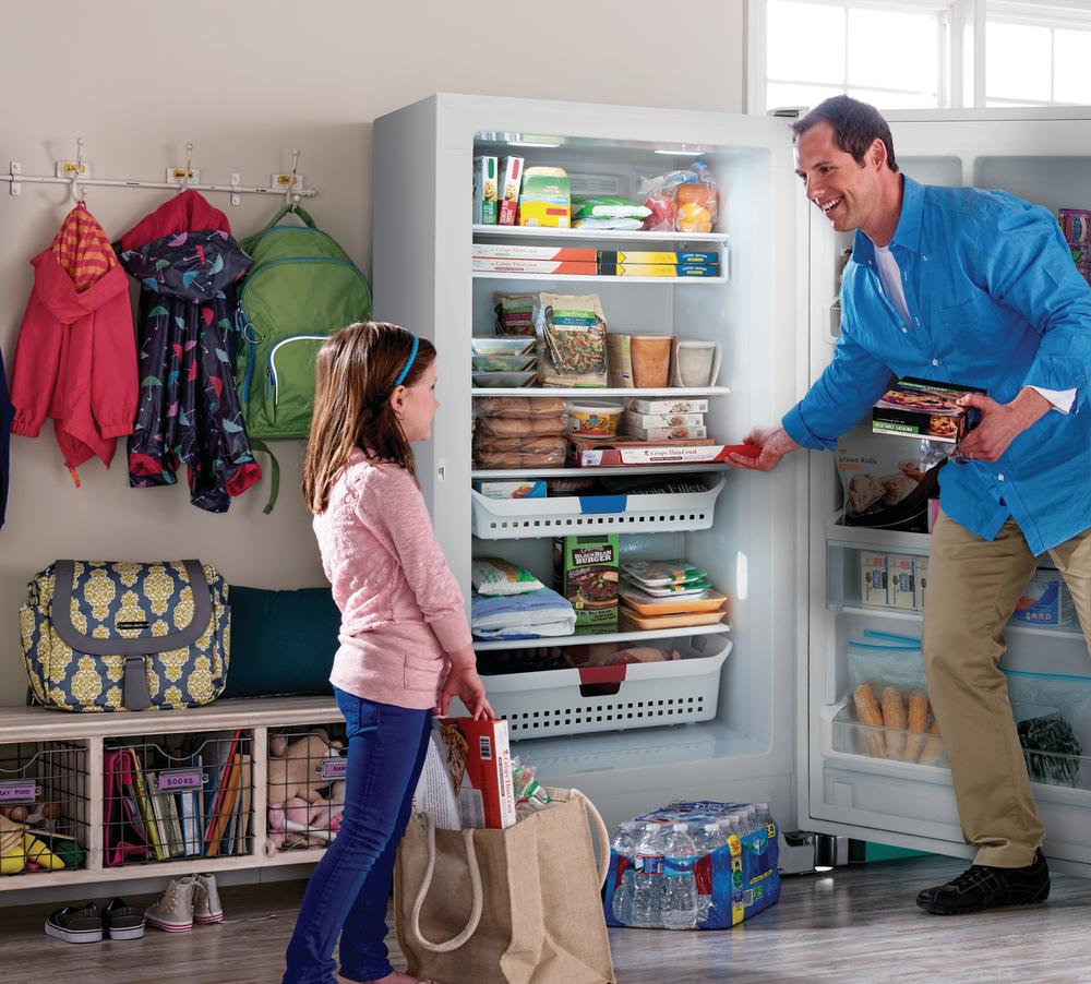 father helps children pack school lunches with upright freezer