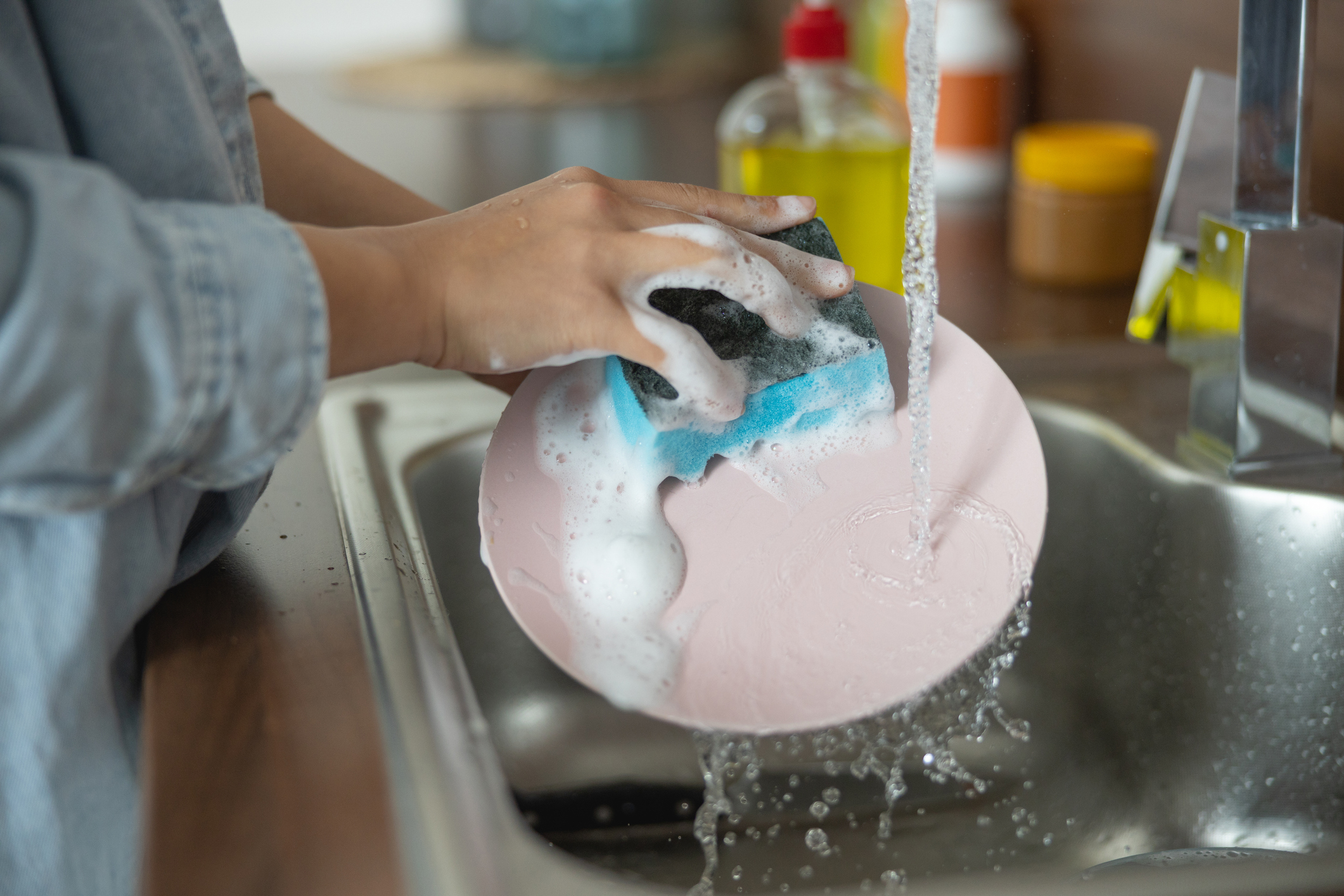 woman washing a plate under the faucet