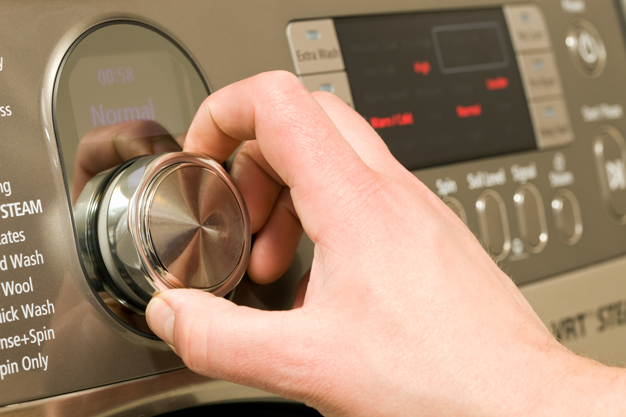 Person operates a rotary dial on a stainless-steel washer 