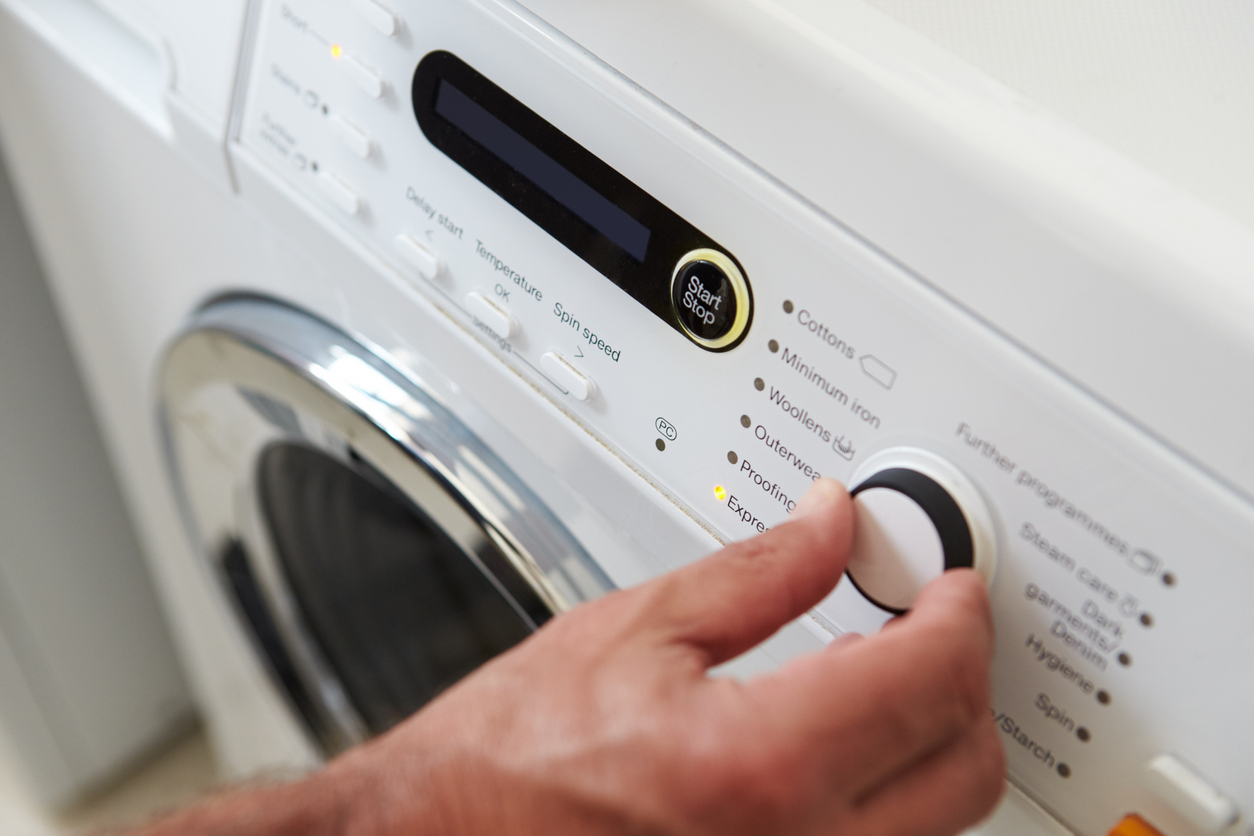 iStock Credit: monkeybusinessimages man choosing cycle program on washing machine