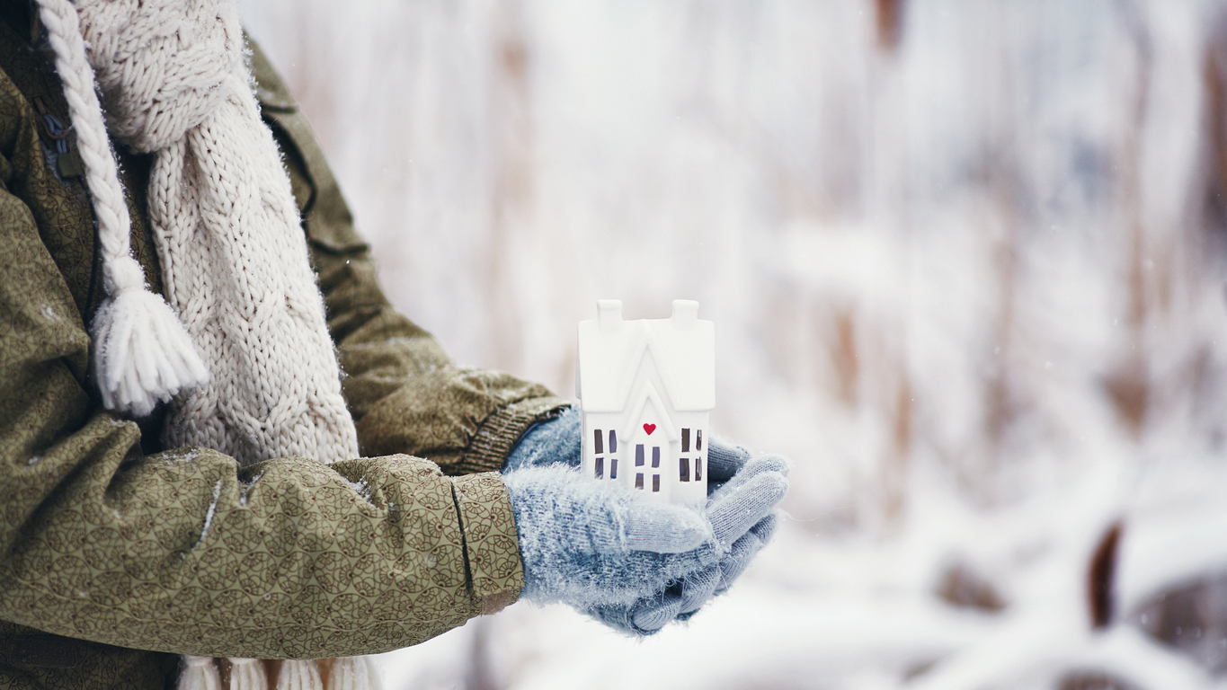 iStock Credit: CatLane outside, winter: mittened hands holding a ceramic house with a heart on it