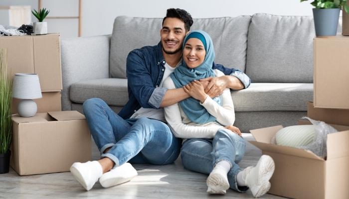 Couple moving into home with boxes everywhere, sitting in front of couch